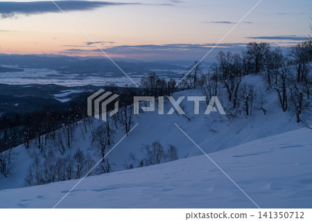 A view of the plains at dusk from a snow-covered ridge. A view of the plains at dusk from a snow-covered ridge. 141350712