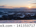 A sunset sinking into a snow-covered plain and a river glowing orange. 141350717