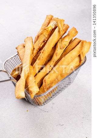 Savory cheese breadsticks in a metal fry basket Savory cheese breadsticks in a metal fry basket 141350896
