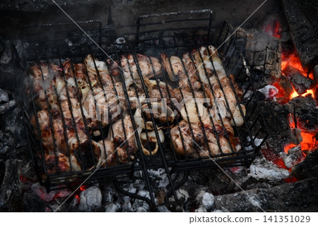 Unrecognizable man cooking seafood on a barbecue grill in the backyard. Unrecognizable man cooking seafood on a barbecue grill in the backyard. 141351029