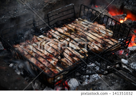 Unrecognizable man cooking seafood on a barbecue grill in the backyard. Unrecognizable man cooking seafood on a barbecue grill in the backyard. 141351032