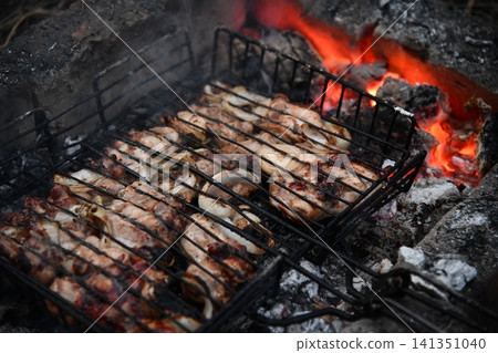 Unrecognizable man cooking seafood on a barbecue grill in the backyard. Unrecognizable man cooking seafood on a barbecue grill in the backyard. 141351040