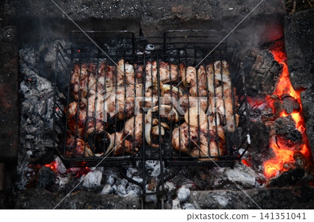Unrecognizable man cooking seafood on a barbecue grill in the backyard. Unrecognizable man cooking seafood on a barbecue grill in the backyard. 141351041