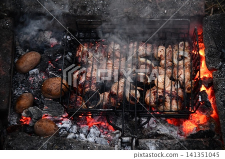 Unrecognizable man cooking seafood on a barbecue grill in the backyard. Unrecognizable man cooking seafood on a barbecue grill in the backyard. 141351045