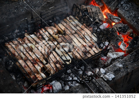 Unrecognizable man cooking seafood on a barbecue grill in the backyard. Unrecognizable man cooking seafood on a barbecue grill in the backyard. 141351052