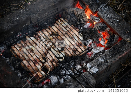 Unrecognizable man cooking seafood on a barbecue grill in the backyard. Unrecognizable man cooking seafood on a barbecue grill in the backyard. 141351053