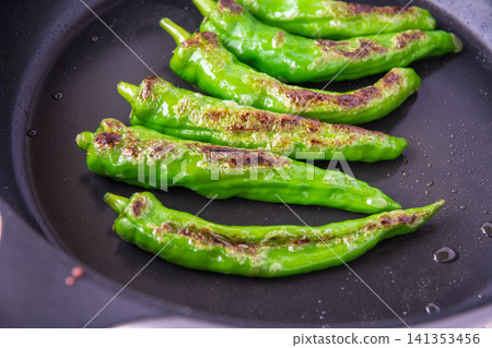 Manganji peppers being cooked in a frying pan Manganji peppers being cooked in a frying pan 141353456