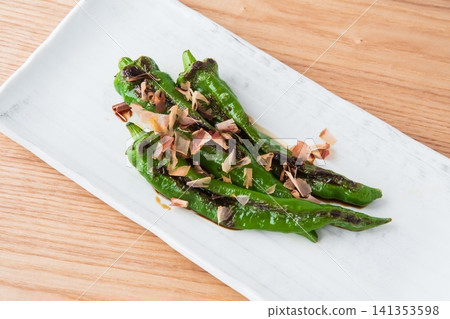 烤滿乾辣椒,撒上鰹魚片和醬油 烤滿乾辣椒,撒上鰹魚片和醬油 141353598