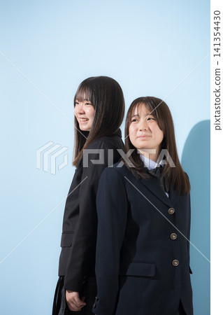 A Japanese high school girl smiles as she gazes at the future against a light blue background; a glimpse into her school life as she and her friend discuss their dreams and future paths. A Japanese high school girl smiles as she gazes at the future against a light blue background; a glimpse into her school life as she and her friend discuss their dreams and future paths. 141354430