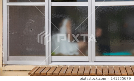 透過老舊毛玻璃窗戶看見的朦朧人物剪影 透過老舊毛玻璃窗戶看見的朦朧人物剪影 141355679