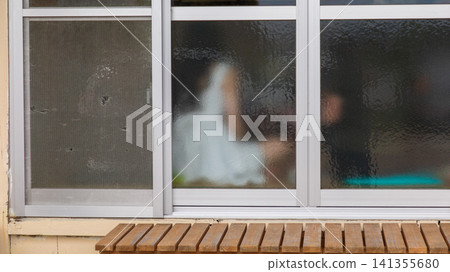 透過老舊毛玻璃窗戶看見的朦朧人物剪影 透過老舊毛玻璃窗戶看見的朦朧人物剪影 141355680