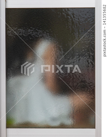 透過老舊毛玻璃窗戶看見的朦朧人物剪影 透過老舊毛玻璃窗戶看見的朦朧人物剪影 141355682