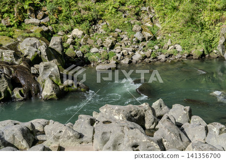 The stream and rugged, strangely shaped rocks of Takachiho Gorge, surrounded by fresh greenery. The stream and rugged, strangely shaped rocks of Takachiho Gorge, surrounded by fresh greenery. 141356700
