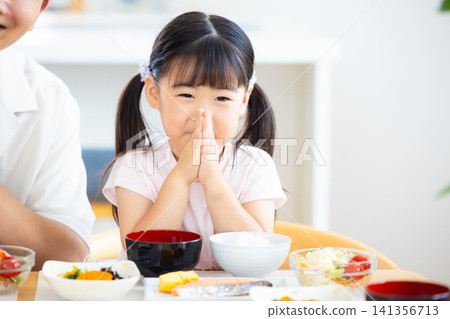 Family meal scene: A girl saying "Itadakimasu" (thank you for the meal). Family meal scene: A girl saying "Itadakimasu" (thank you for the meal). 141356713