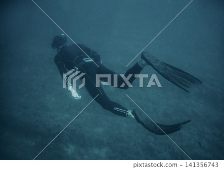 Freediver Swimming Underwater in Blue Ocean with Fins Freediver Swimming Underwater in Blue Ocean with Fins 141356743