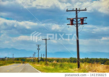 Rural Road with Power Lines and Utility Poles Under Cloudy Sky Rural Road with Power Lines and Utility Poles Under Cloudy Sky 141356823