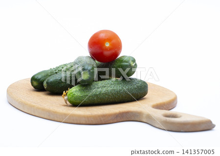 Ripe red tomatoes and cucumbers on a wooden board against a white background Ripe red tomatoes and cucumbers on a wooden board against a white background 141357005