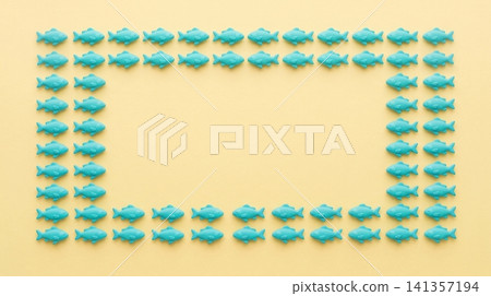 Turquoise plastic fish figurines arranged in rectangular frame pattern against soft yellow background surface with collection identical turquoise Turquoise plastic fish figurines arranged in rectangular frame pattern against soft yellow background surface with collection identical turquoise 141357194