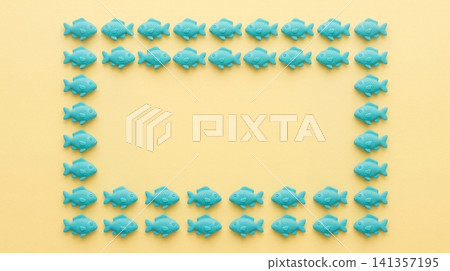 Turquoise plastic fish figurines arranged in rectangular frame pattern against soft yellow background surface with collection identical turquoise 141357195
