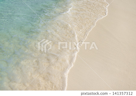 Gentle wave washing over smooth white sand, soft foam edge on tropical beach closeup. Delicate water texture meeting clean shore, bright natural pattern in daylight. Fresh minimal background for spa, Gentle wave washing over smooth white sand, soft foam edge on tropical beach closeup. Delicate water texture meeting clean shore, bright natural pattern in daylight. Fresh minimal background for spa, 141357312