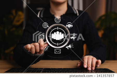 Target audience marketing concept. Woman using magnifying glass focusing on an icon with digital marketing, communication, analytics symbol represent audience targeting, CRM, customer insight strategy Target audience marketing concept. Woman using magnifying glass focusing on an icon with digital marketing, communication, analytics symbol represent audience targeting, CRM, customer insight strategy 141357857