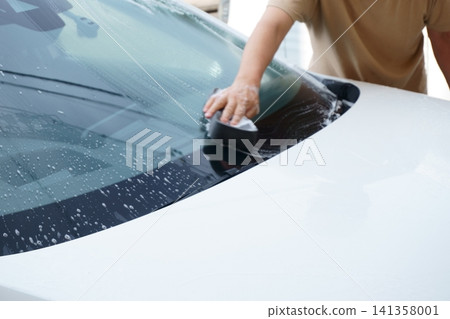 Wash the car's windshield with a sponge Wash the car's windshield with a sponge 141358001