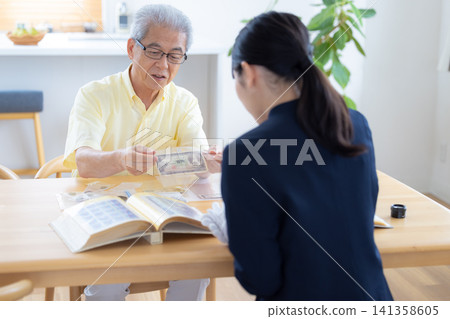On-site appraisal service: A senior man having his stamps and old coins appraised at his home. On-site appraisal service: A senior man having his stamps and old coins appraised at his home. 141358605