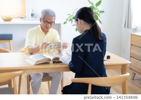 現場鑑定服務:一位老人在家中請人鑑定他的郵票和古幣。 現場鑑定服務:一位老人在家中請人鑑定他的郵票和古幣。 141358606