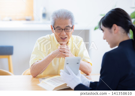 現場鑑定服務:一位老人在家中請人鑑定他的郵票和古幣。 現場鑑定服務:一位老人在家中請人鑑定他的郵票和古幣。 141358610
