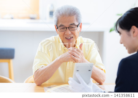 現場鑑定服務:一位老人在家中請人鑑定他的郵票和古幣。 現場鑑定服務:一位老人在家中請人鑑定他的郵票和古幣。 141358611