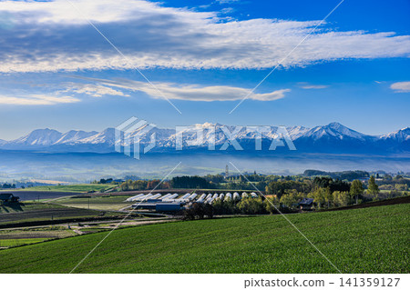 A magnificent early summer landscape with snow-capped ridgelines visible in the distance and hills painted in a patchwork of colors. A magnificent early summer landscape with snow-capped ridgelines visible in the distance and hills painted in a patchwork of colors. 141359127