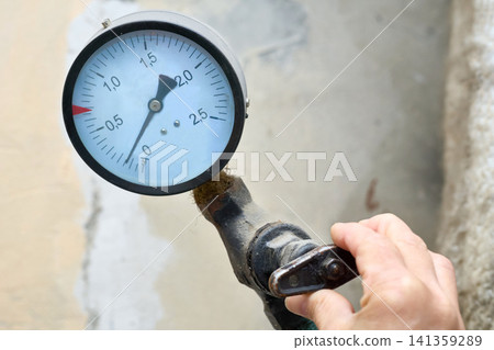 Hand regulating the water supply.Pressure sensor in basement Hand regulating the water supply.Pressure sensor in basement 141359289