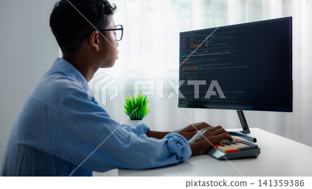 Asian male IT specialist with glasses coding software or programming on desktop computer at home office desk. Concentrated smart student studying computer science online. Asian male IT specialist with glasses coding software or programming on desktop computer at home office desk. Concentrated smart student studying computer science online. 141359386