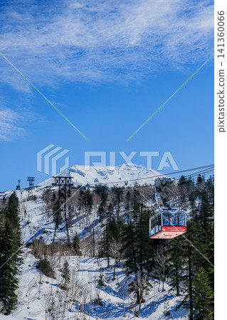 An aerial stroll over Mount Asahidake in winter. The contrast between the red gondola and the snowy landscape. An aerial stroll over Mount Asahidake in winter. The contrast between the red gondola and the snowy landscape. 141360066