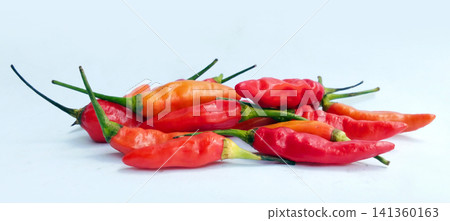 Piles of fresh red and orange bird's eye chilies on a white surface. Piles of fresh red and orange bird's eye chilies on a white surface. 141360163