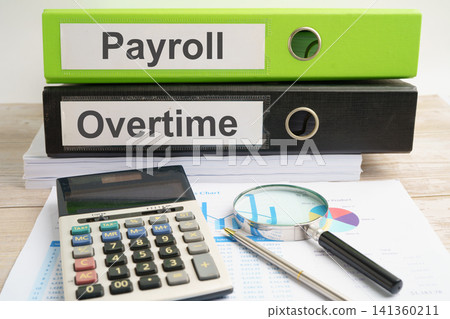Payroll Overtime. binder with graph and calculator in business office. Payroll Overtime. binder with graph and calculator in business office. 141360211