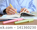 A woman's hands while studying for an exam. 141360230