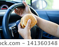 Asian woman driver hold and eat hamburger food in car. 141360348