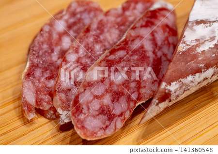 Sliced fuet sausage on wooden board closeup Sliced fuet sausage on wooden board closeup 141360548