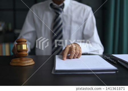 Lawyer Reviewing Contract and Documents with Gavel on Desk. Lawyer Reviewing Contract and Documents with Gavel on Desk. 141361871