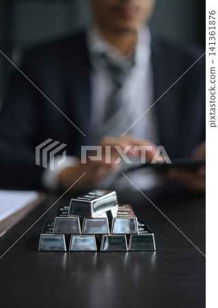 Stacked Silver Bars on the table with businessman managing his precious metals portfolio in office desk. Stacked Silver Bars on the table with businessman managing his precious metals portfolio in office desk. 141361876