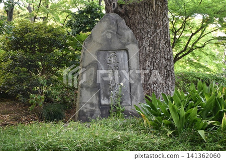 A historical stone monument of the former Yasuda Garden stands quietly at the base of a large tree. A historical stone monument of the former Yasuda Garden stands quietly at the base of a large tree. 141362060