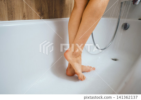 Female feet in bathtub during shower time in bathroom Female feet in bathtub during shower time in bathroom 141362137