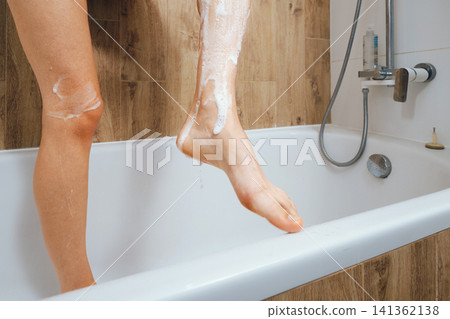 Woman washing foot in bathtub with soap during morning routine Woman washing foot in bathtub with soap during morning routine 141362138