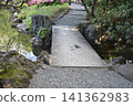 A historical stone bridge in a Japanese garden surrounded by lush green trees. 141362983
