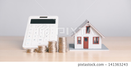 House model with calculator and coin stacks on wooden table, representing mortgage calculation, home loan budget, property tax, real estate cost, and financial planning. House model with calculator and coin stacks on wooden table, representing mortgage calculation, home loan budget, property tax, real estate cost, and financial planning. 141363243