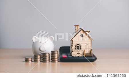 White piggy bank, wooden house, coin stacks and calculator, symbolizing home savings, mortgage calculation, property budget, real estate finance, and loan planning. White piggy bank, wooden house, coin stacks and calculator, symbolizing home savings, mortgage calculation, property budget, real estate finance, and loan planning. 141363260