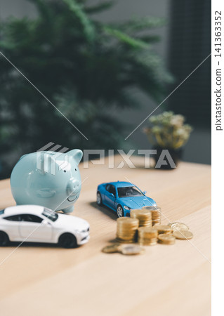Blue piggy bank with blue and white toy cars and coin stacks, representing car savings options, auto loan planning, and budget preparation for vehicle purchase. 141363352