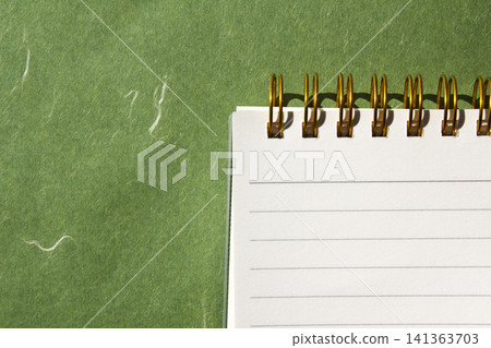 It is a small notebook placed on a green background. It is a small notebook placed on a green background. 141363703