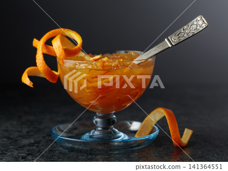 Homemade orange marmalade in a glass bowl on a black background. Homemade orange marmalade in a glass bowl on a black background. 141364551